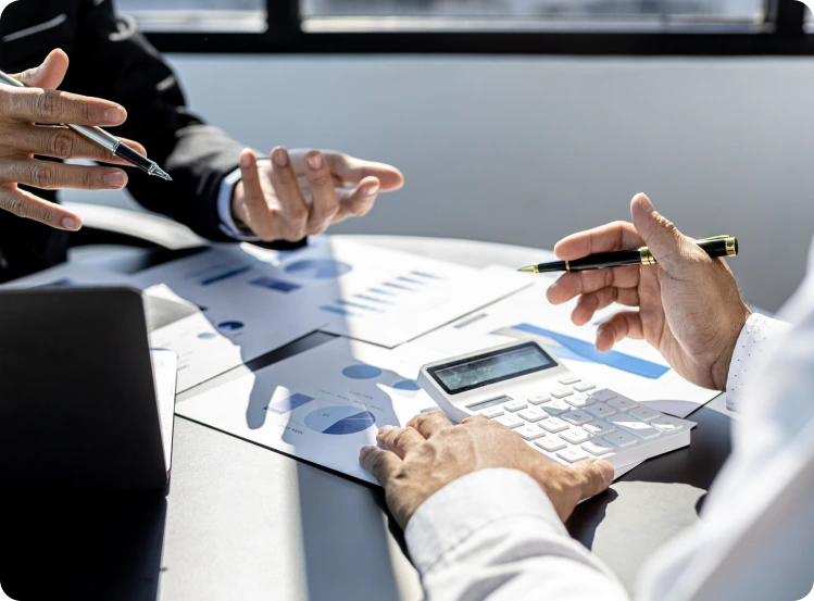 Deux personnes analysant des graphiques financiers et un budget avec une calculatrice