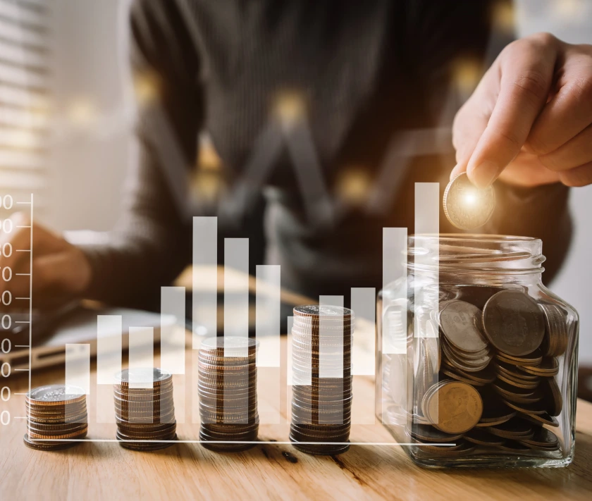 Personne qui glisse une pièce dans un bocal avec des piles de pièces croissantes représentant l'épargne progressive